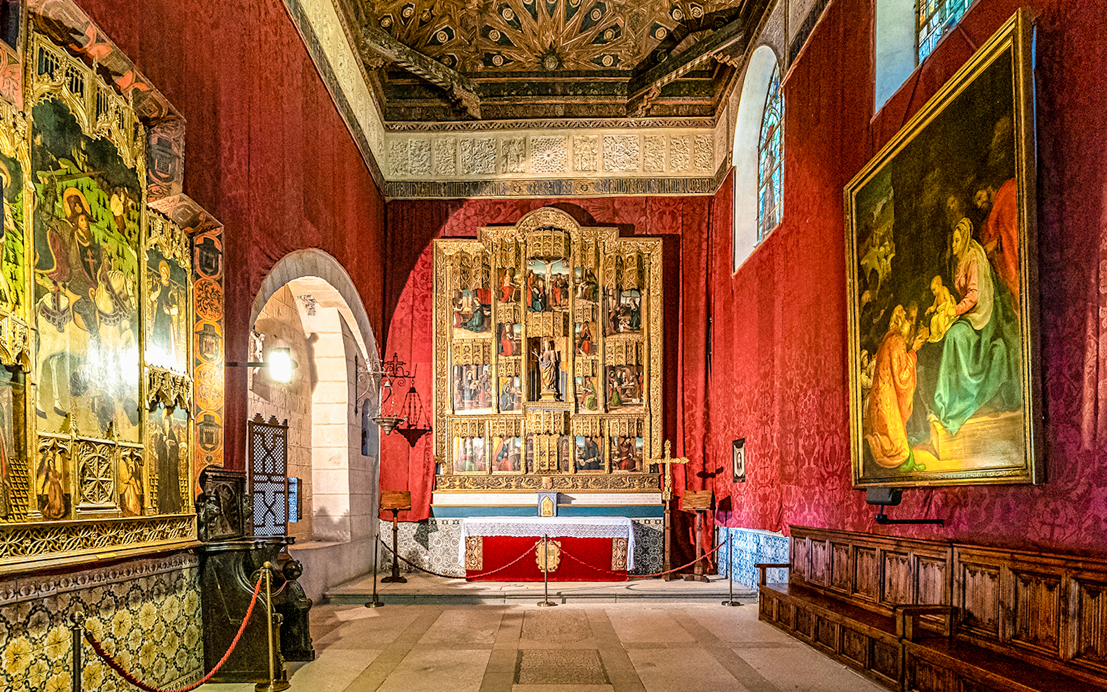 Alcazar of Segovia interior with ornate frescoes and religious artwork in a historic chapel setting.