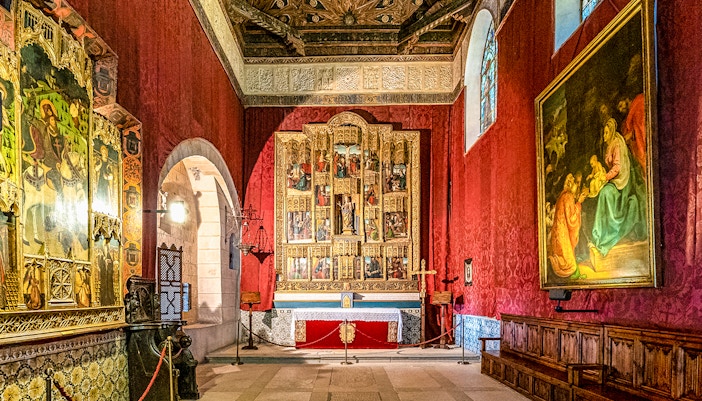Alcazar of Segovia interior with ornate frescoes and religious artwork in a historic chapel setting.