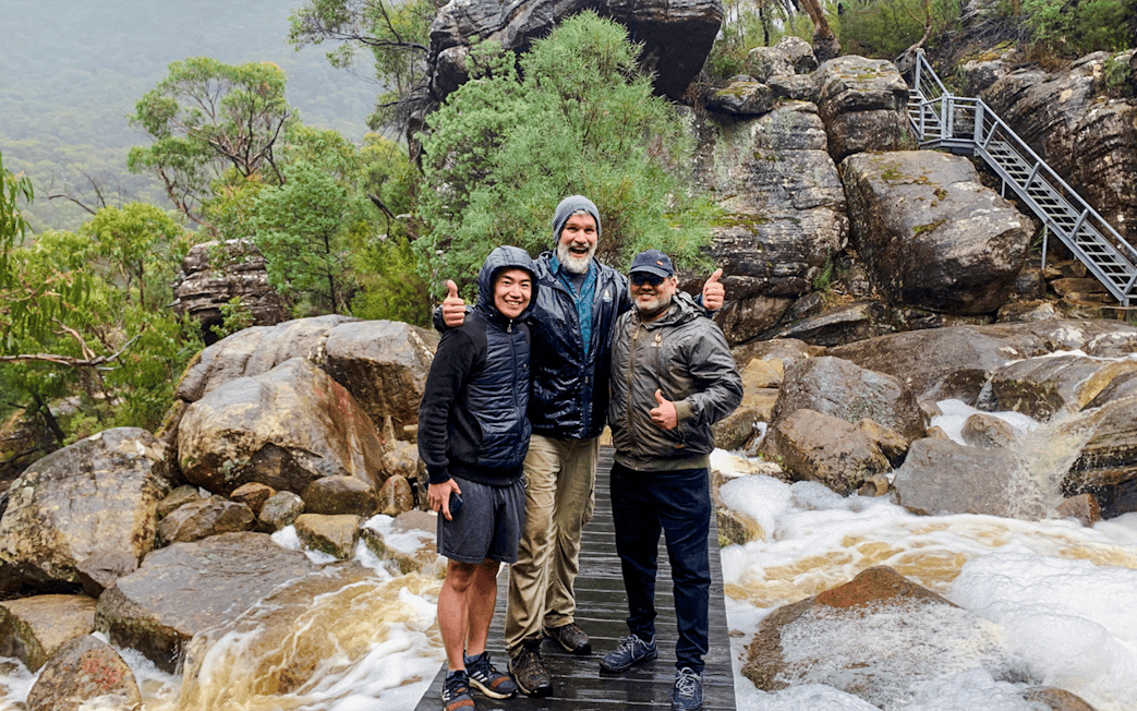 Guide and guests on a rocky trail in a lush forest setting.