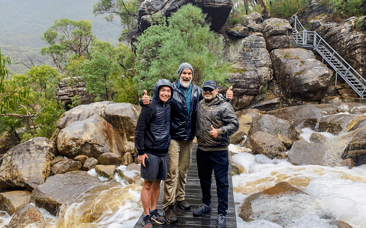 Guide and guests on a rocky trail in a lush forest setting.