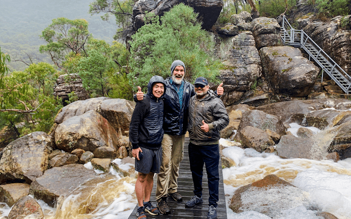 Guide and guests on a rocky trail in a lush forest setting.