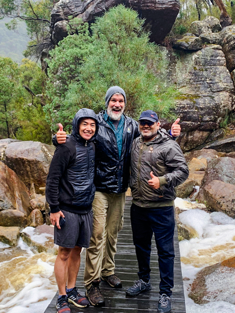 Guide and guests on a rocky trail in a lush forest setting.