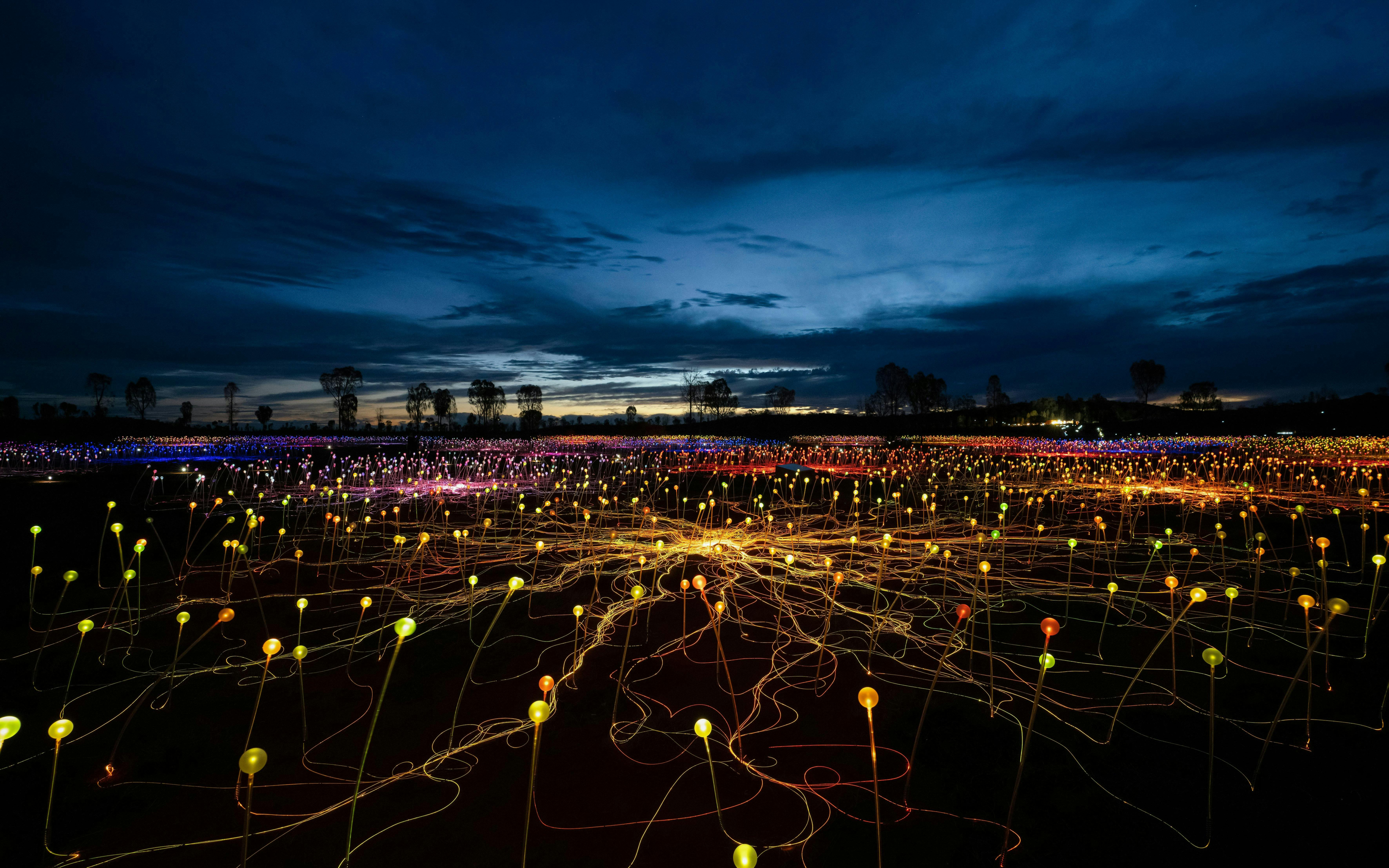 Uluru Field of Light installation at sunrise with colorful illuminated spheres.