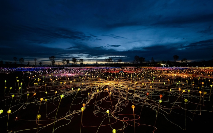 Uluru Field of Light installation at sunrise with colorful illuminated spheres.