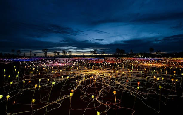 Uluru Field of Light installation at sunrise with colorful illuminated spheres.