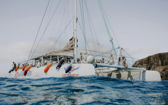 Catamaran sailing near Papagayo Beaches, Lanzarote, with passengers on deck.