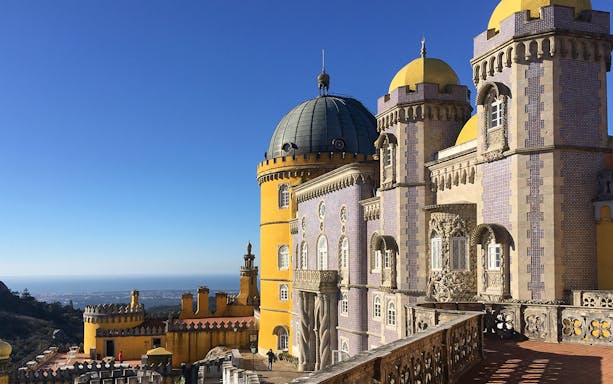 Pena Palace in Sintra with colorful towers and ocean view on a sunny day.