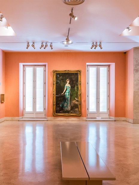 Thyssen Museum gallery with paintings on orange walls in Madrid, Spain.