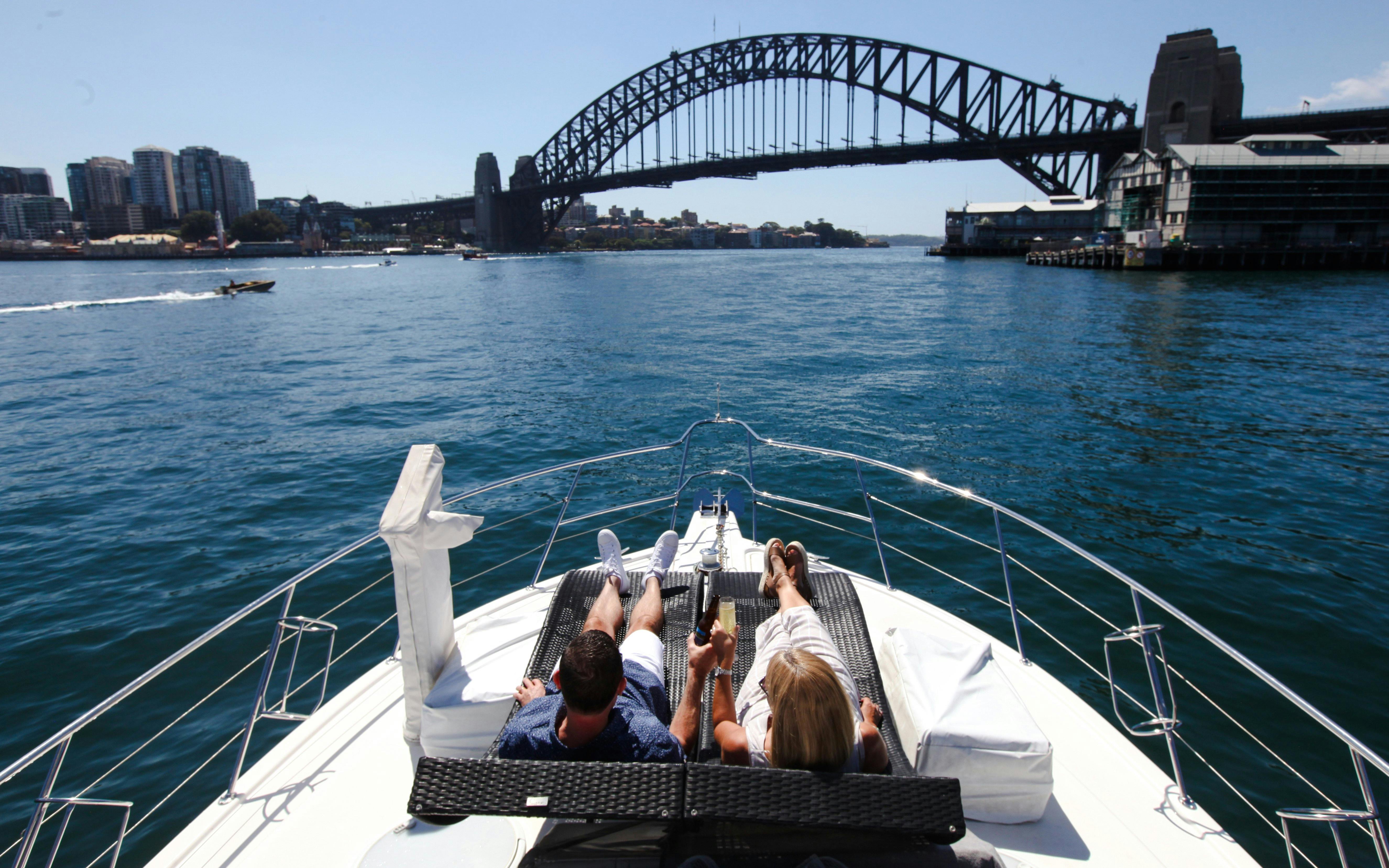 Couple relaxing on a boat with Sydney Harbour Bridge in view during a sightseeing cruise.