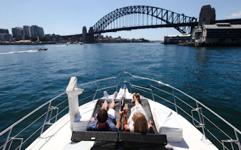 Couple relaxing on a boat with Sydney Harbour Bridge in view during a sightseeing cruise.