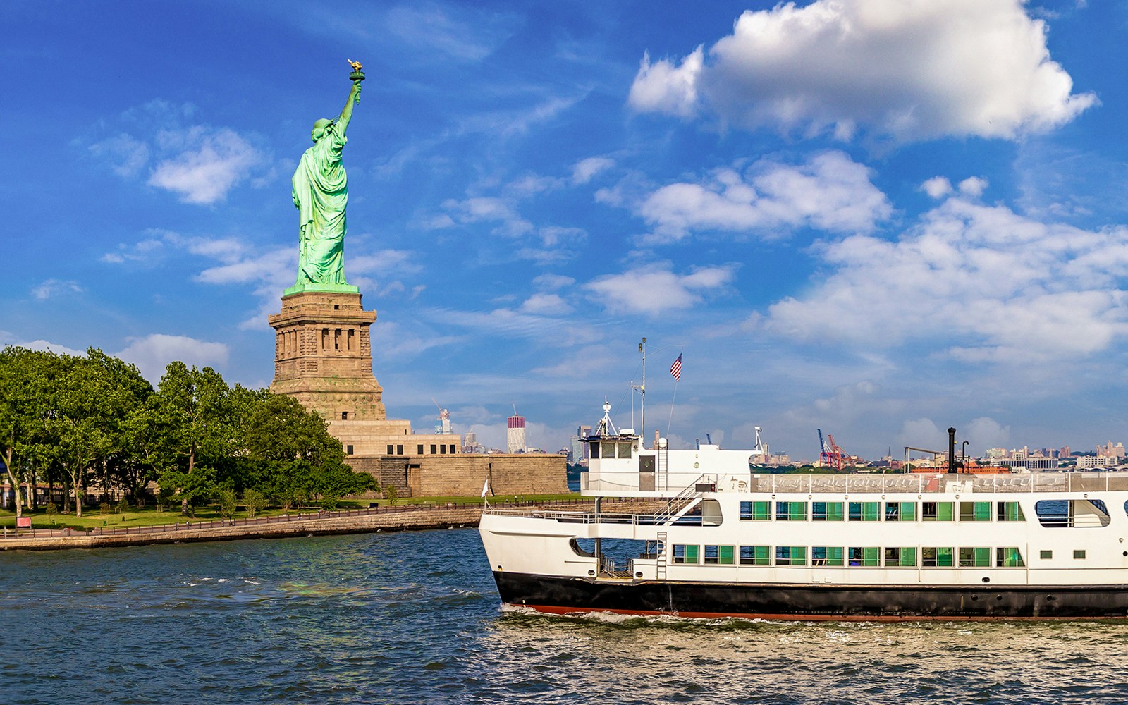 Passengers enjoying the 1 Hour Statue of Liberty Sightseeing Cruise with a clear view of the iconic statue and New York skyline in the background