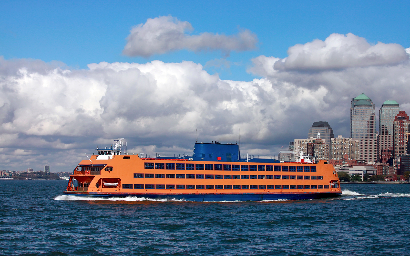 Staten Island ferry crossing New York Harbor with city skyline in the background.