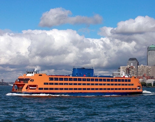 Staten Island ferry crossing New York Harbor with city skyline in the background.