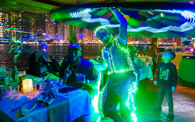 Performer in LED costume entertaining guests on a Dubai Creek dinner cruise.