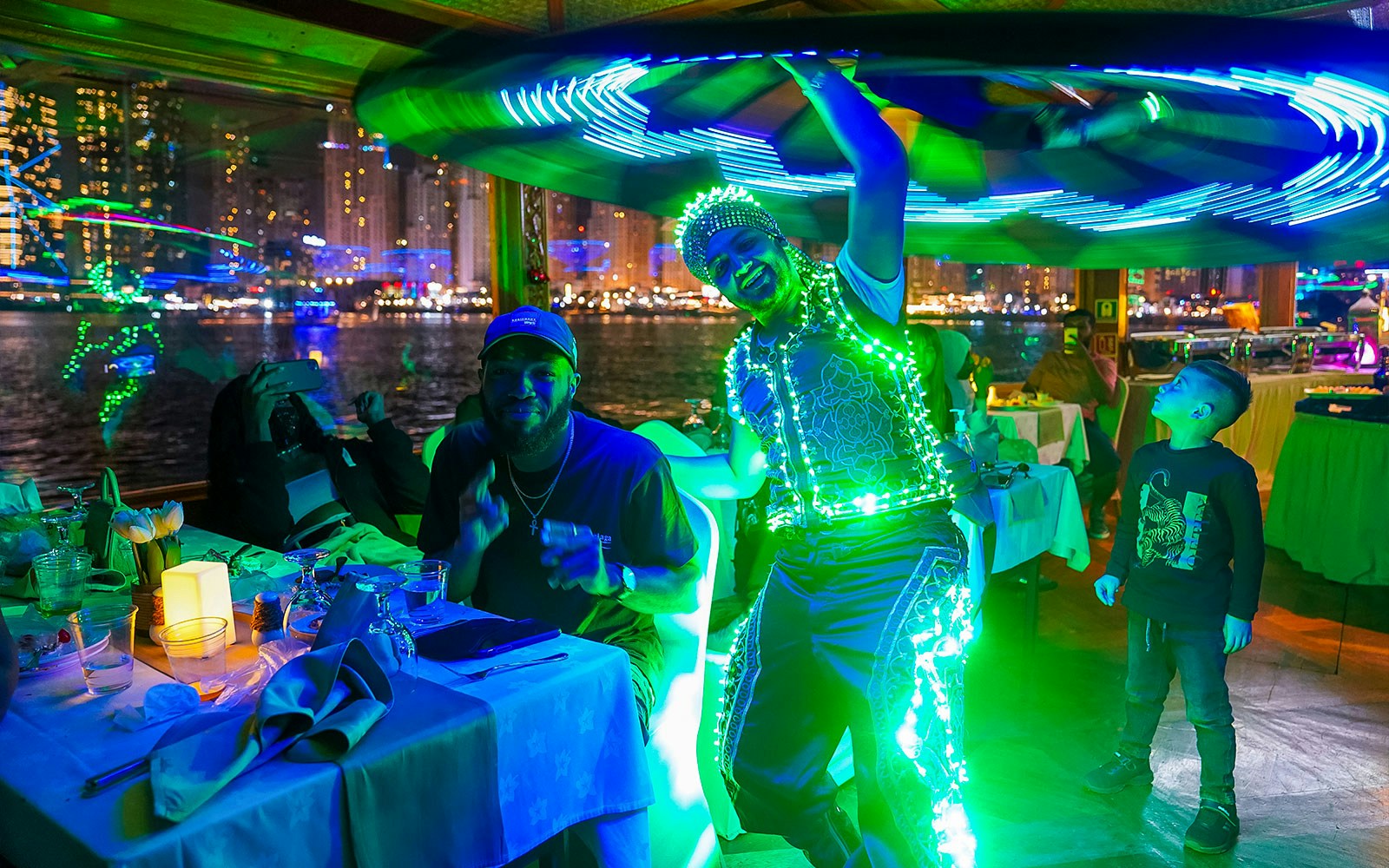 Dhow boat on Dubai Creek with guests enjoying dinner and live entertainment.