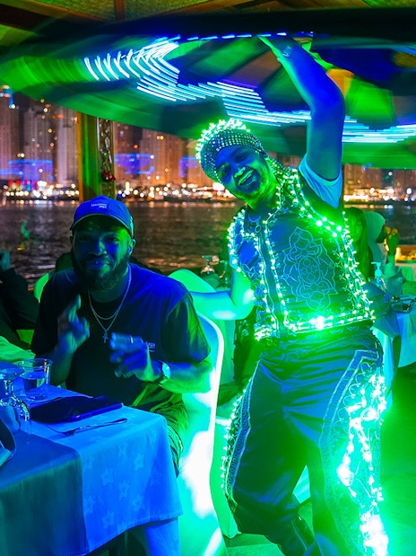 Performer in LED costume entertaining guests on a Dubai Creek dinner cruise.