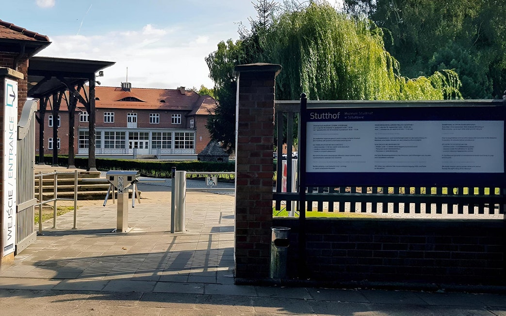 Entrance to Stutthof Concentration Camp with informational sign and turnstile.