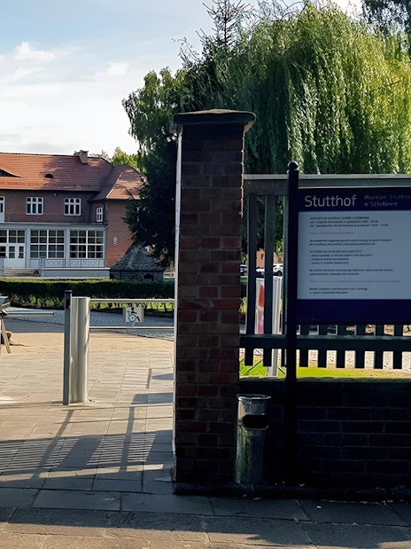 Entrance to Stutthof Concentration Camp with informational sign and turnstile.