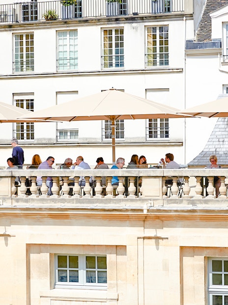 Terrace cafe at Picasso Museum, Paris, with people dining under umbrellas.