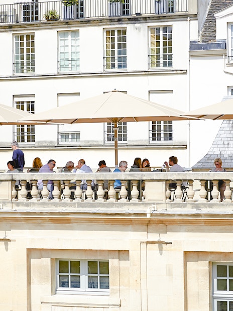 Terrace cafe at Picasso Museum, Paris, with people dining under umbrellas.