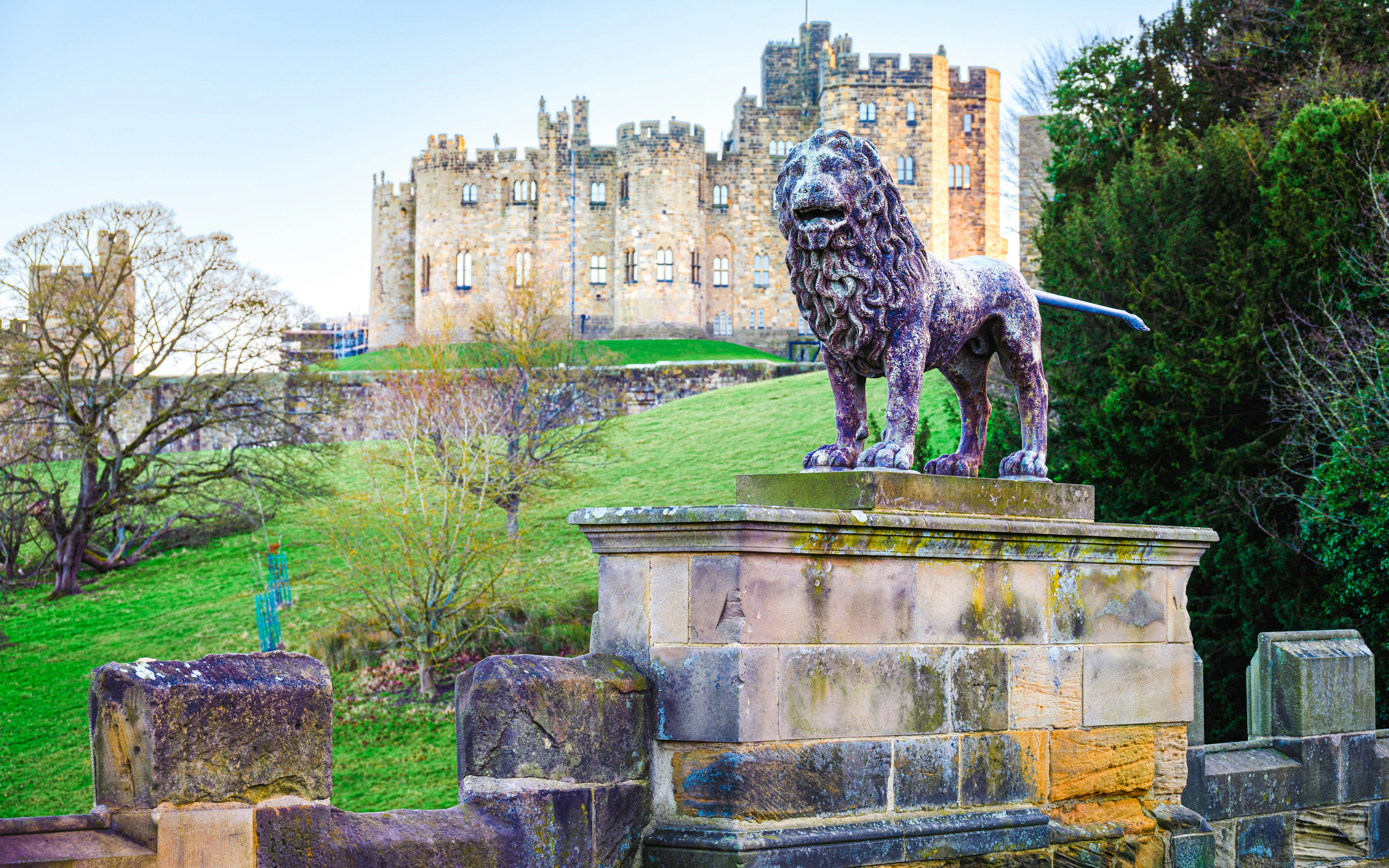 Stone lion statue with Alnwick Castle in the background, Northumberland, England.