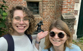 Two people smiling in front of a statue during a self-guided city exploration in Haarlem.