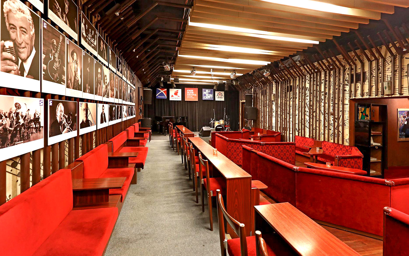 Interior seating and stage at Reduta Jazz Club, Prague, with jazz musician portraits on the wall.
