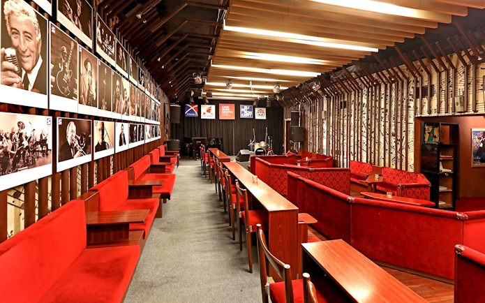 Interior seating and stage at Reduta Jazz Club, Prague, with jazz musician portraits on the wall.