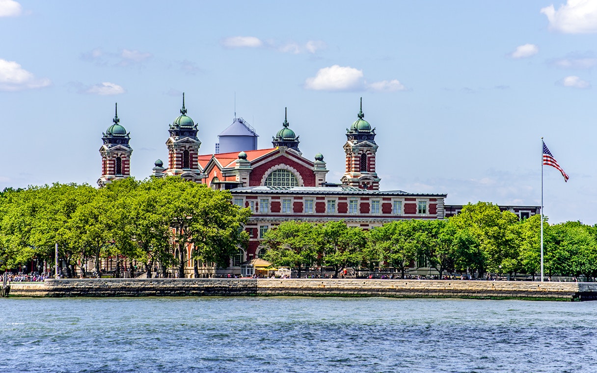 Ellis Island with historic building viewed from East River cruise near Statue of Liberty.