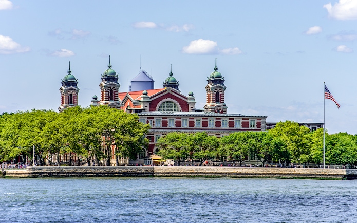 Ellis Island with historic building viewed from East River cruise near Statue of Liberty.