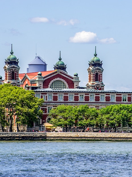 Ellis Island with historic building viewed from East River cruise near Statue of Liberty.