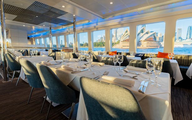 Luxury catamaran dining setup with Sydney Opera House view, part of a lunch cruise with deluxe buffet.