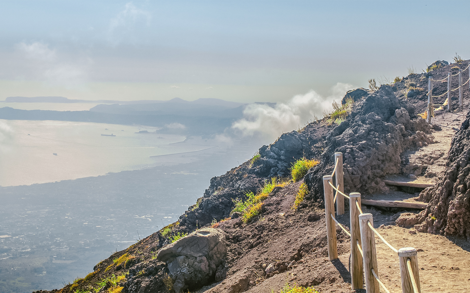Pathway along Mount Vesuvius with view of Naples coastline in the distance.