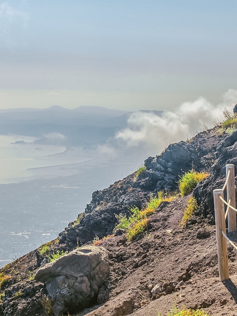 Pathway along Mount Vesuvius with view of Naples coastline in the distance.