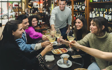 Group enjoying wine and petiscos at a bar during The Original Porto Petiscos Crawl.