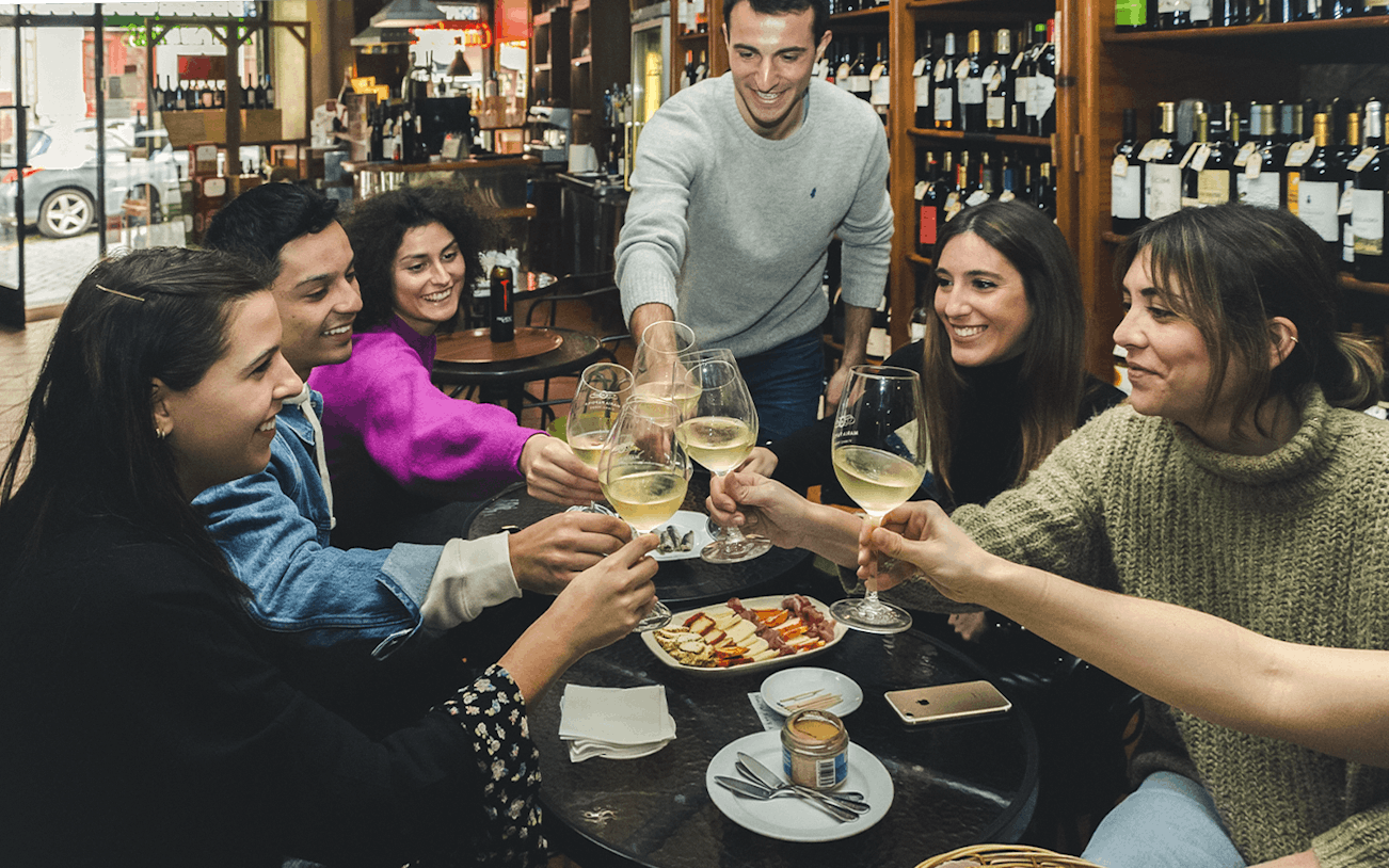 Group enjoying wine and petiscos at a bar during The Original Porto Petiscos Crawl.