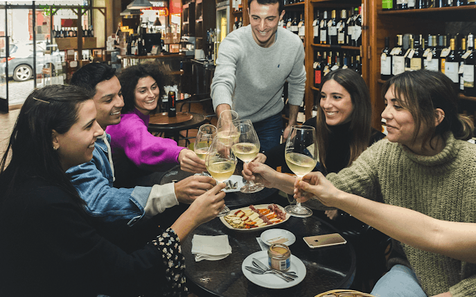 Group enjoying wine and petiscos at a bar during The Original Porto Petiscos Crawl.