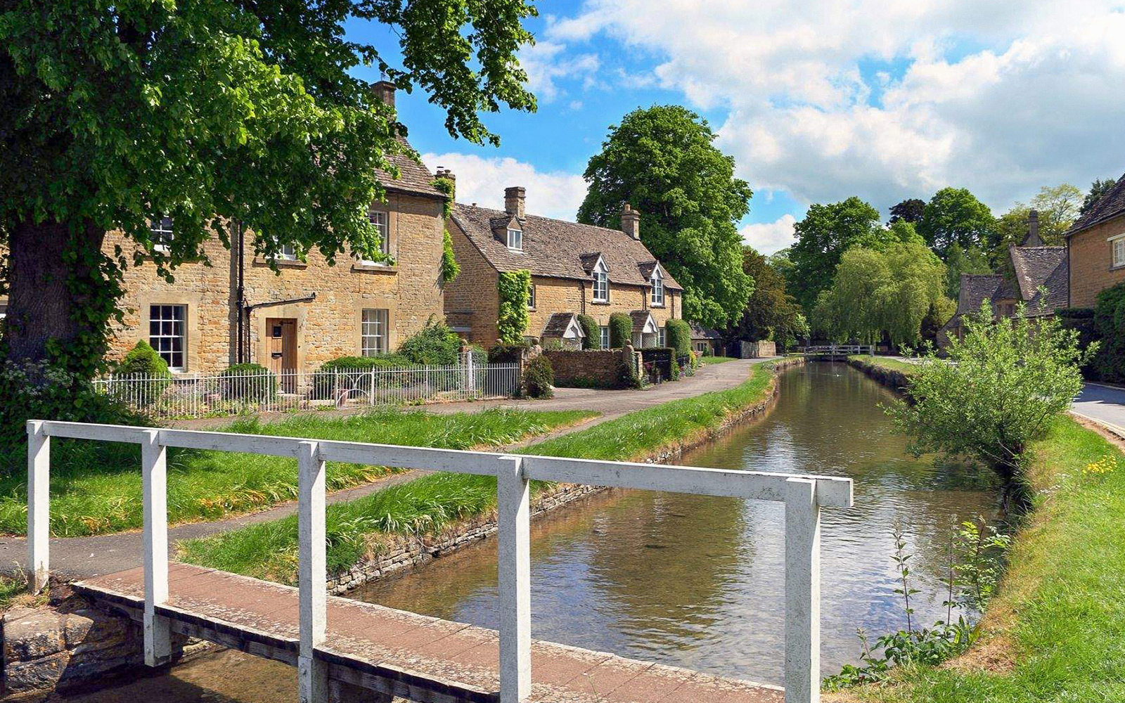 Cotswolds village scene with stone cottages and a canal, part of Stratford, Oxford, Cotswolds & Warwick Castle Tour.