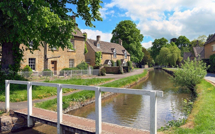 Cotswolds village scene with stone cottages and a canal, part of Stratford, Oxford, Cotswolds & Warwick Castle Tour.