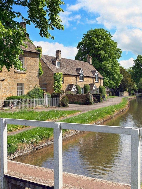 Cotswolds village scene with stone cottages and a canal, part of Stratford, Oxford, Cotswolds & Warwick Castle Tour.
