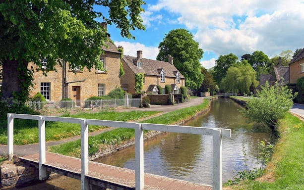 Cotswolds village scene with stone cottages and a canal, part of Stratford, Oxford, Cotswolds & Warwick Castle Tour.