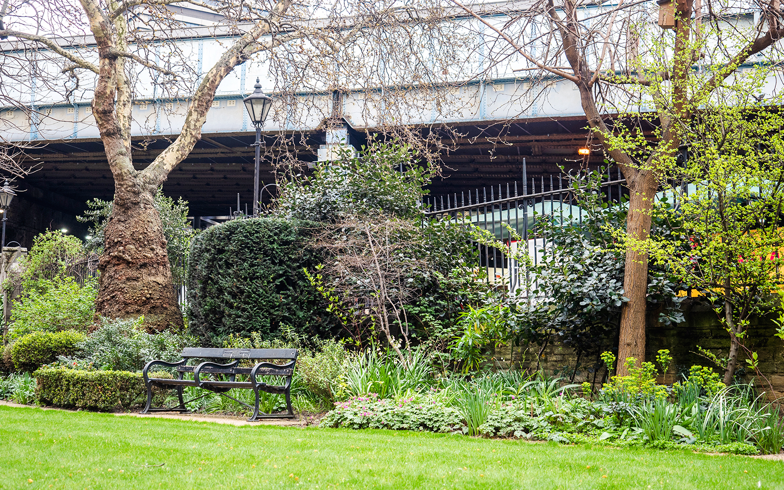 Bench in Southwark Cathedral garden surrounded by trees and greenery, London, England.
