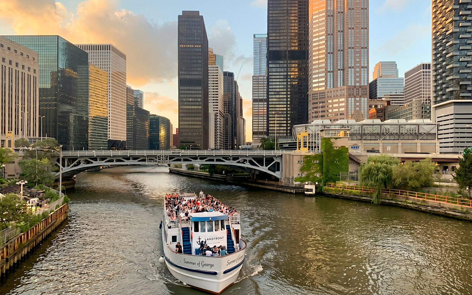 Cruise boat on Chicago River with city skyscrapers in the background.