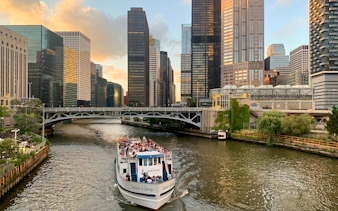 Cruise boat on Chicago River with city skyscrapers in the background.