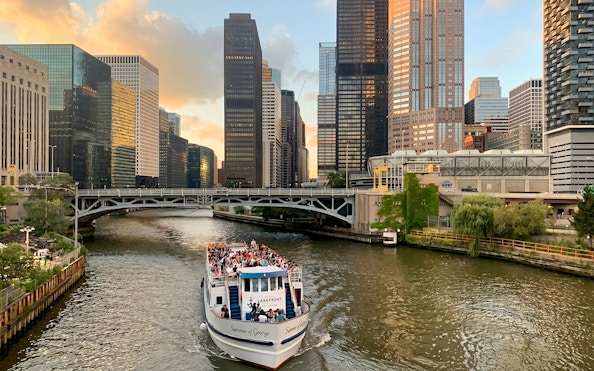 Cruise boat on Chicago River with city skyscrapers in the background.