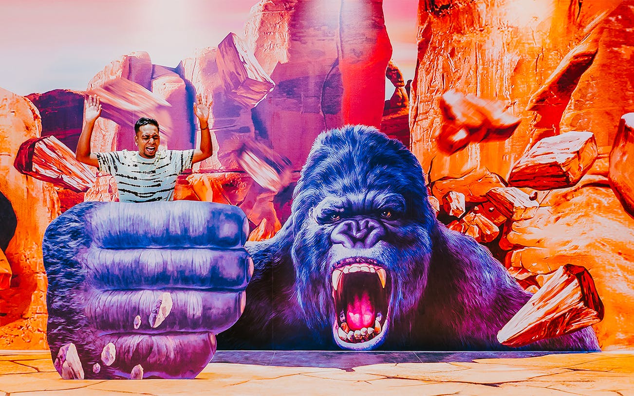 Man posing with giant gorilla illusion at Trick Eye Museum, Singapore.