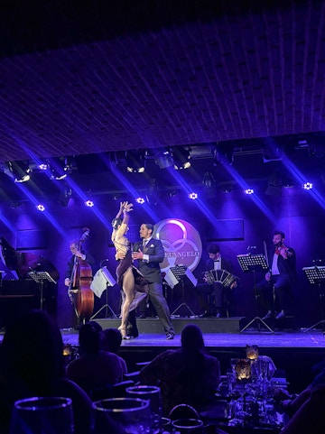 Dancers performing tango on stage with live band in Buenos Aires.