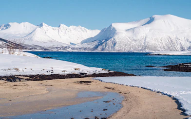 Snowy mountains and blue fjord in Sommarøy, Tromsø.