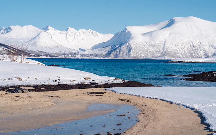 Snowy mountains and blue fjord in Sommarøy, Tromsø.