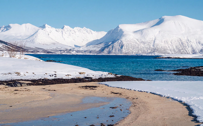 Snowy mountains and blue fjord in Sommarøy, Tromsø.